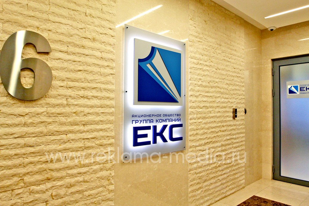 Вид вывески слева на фоне входной двери в офис организации
